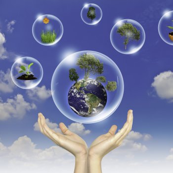 Eco concept : Hand hold earth ,tree and flower in bubbles against the sun and the blue sky